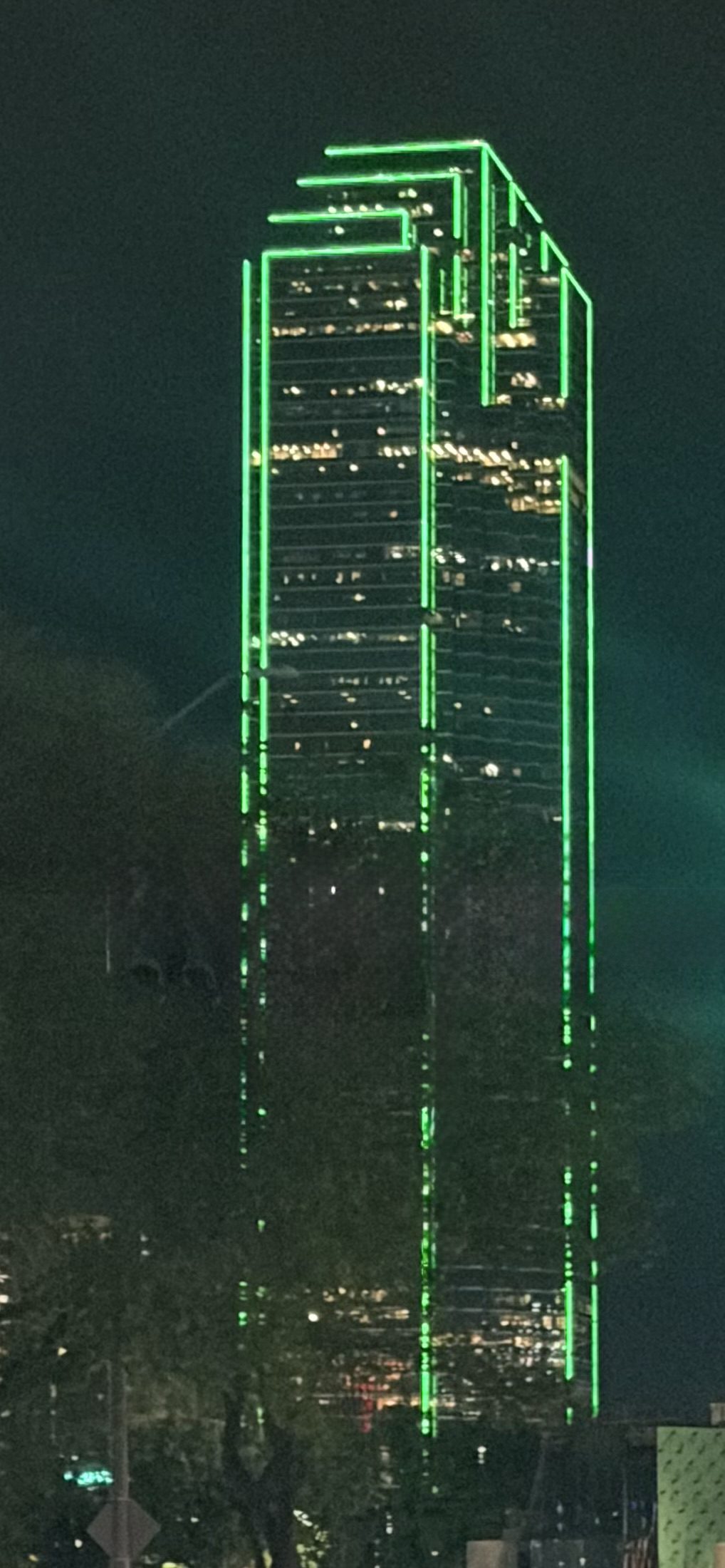 The green-outlined Bank of America Plaza tower lit at night, a backdrop to Christmas things to do in Dallas