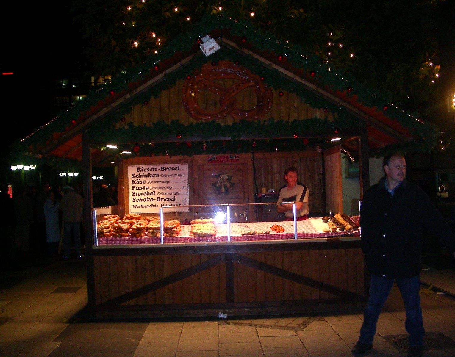 A wooden German-style Christmas market food stall lit up at night