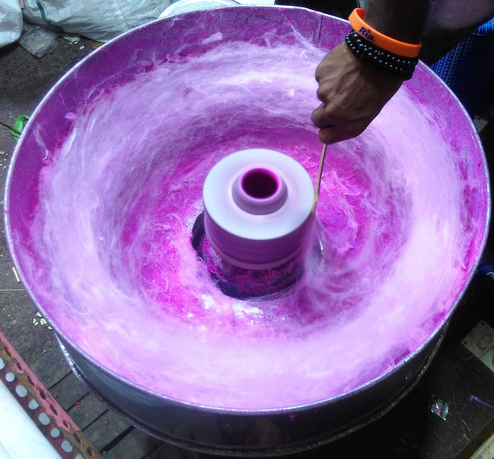Cotton candy being spun in a bright purple machine at a fairground stall