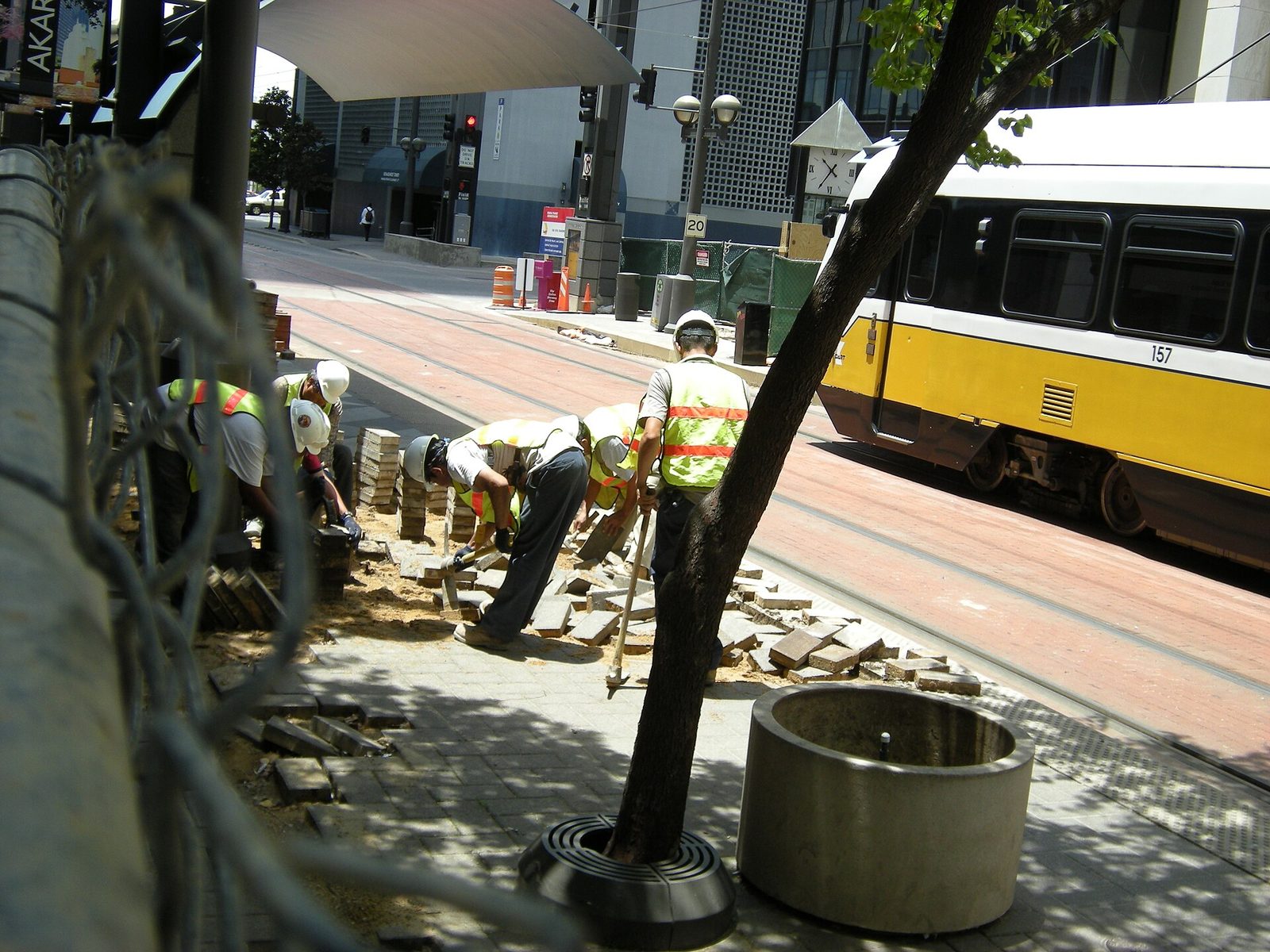 Workers laying a new sidewalk beside a DART bus in downtown Dallas