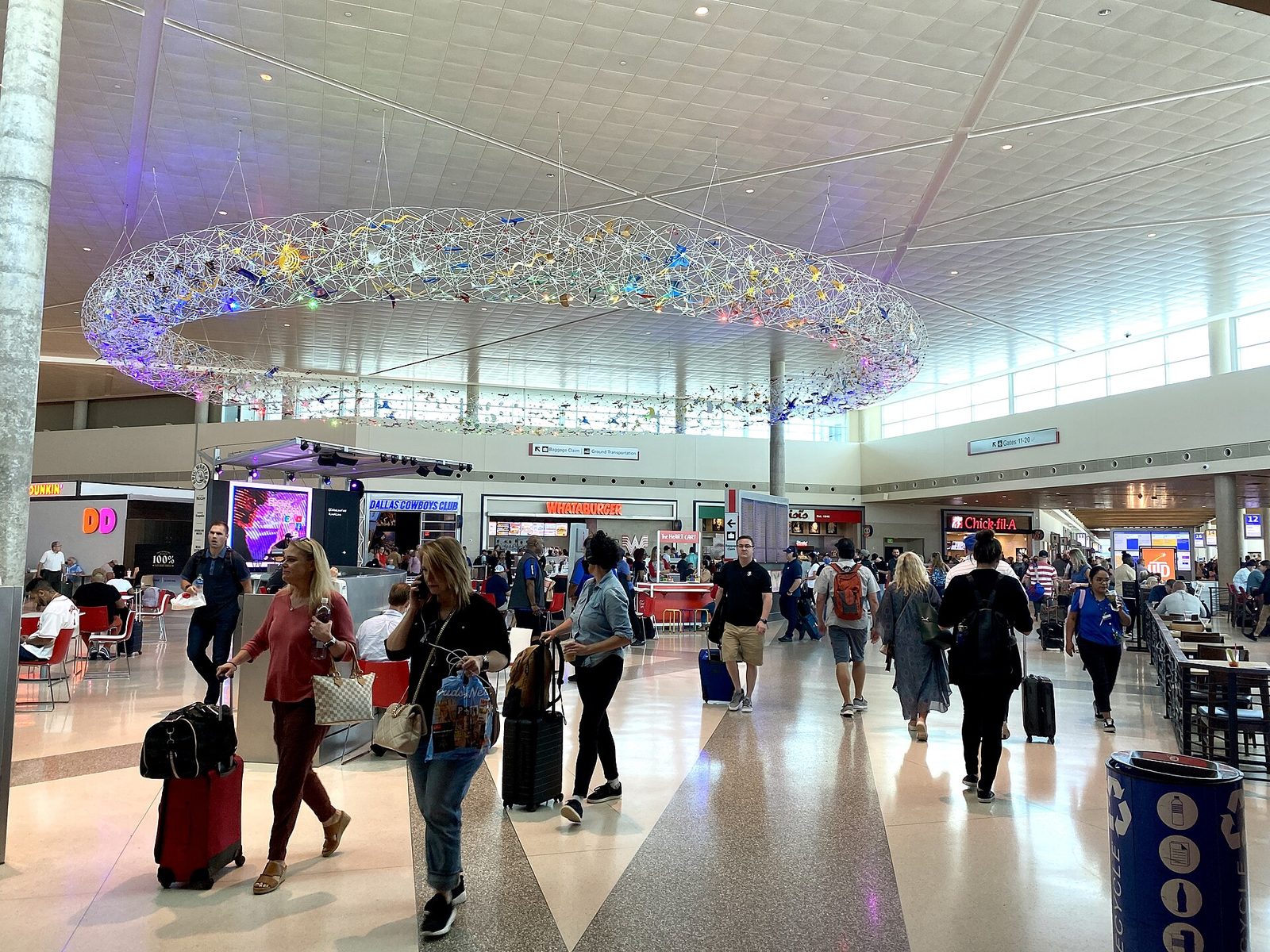 Travelers with rolling suitcases in the bright main terminal concourse at Dallas Love Field