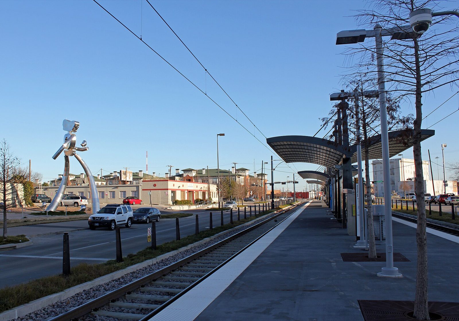 Deep Ellum DART light rail station in Dallas with the Walking Tall sculpture beside the platform