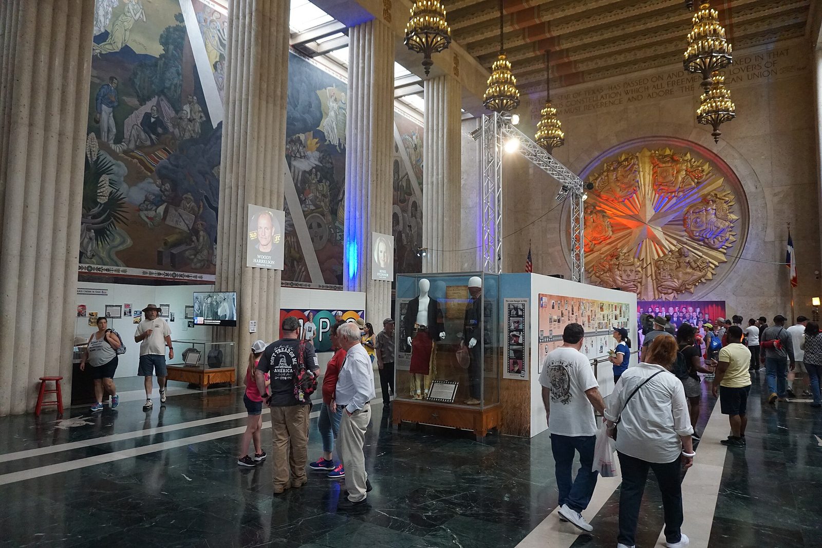 Crowds inside the Hall of State at Fair Park during the State Fair of Texas, with murals and a stained glass window