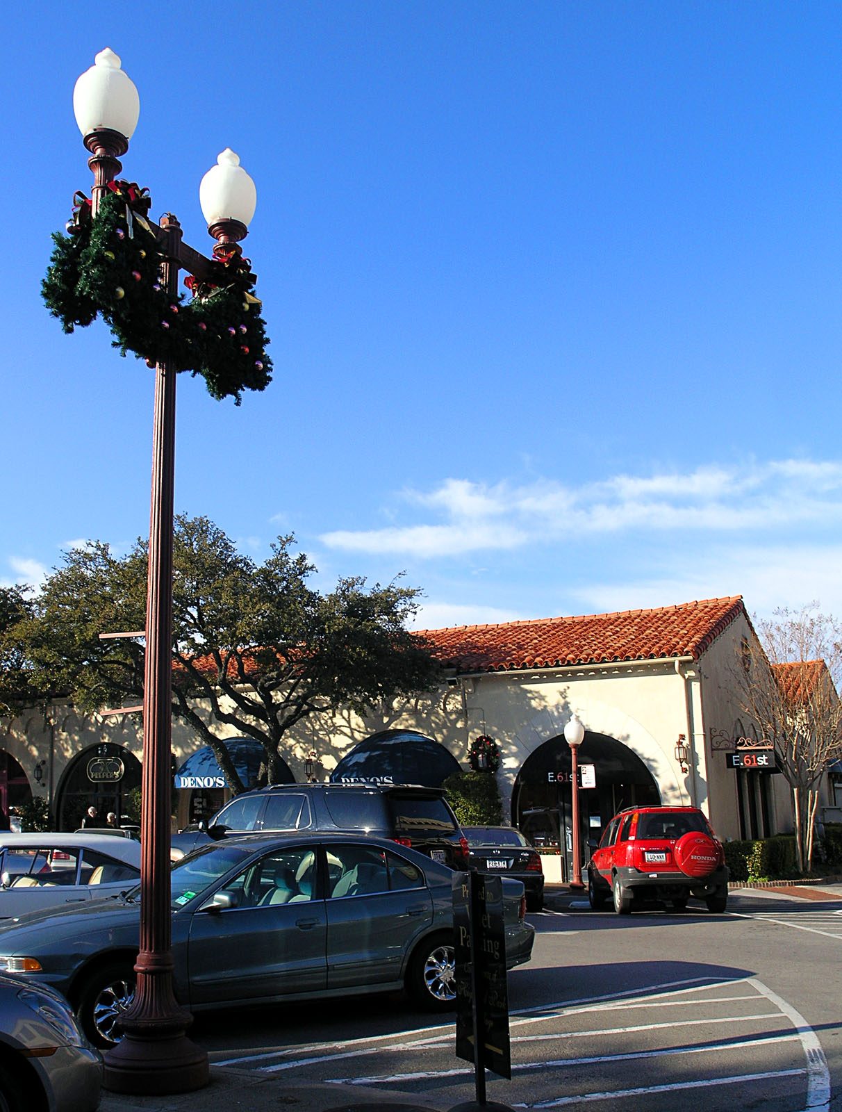 A lamp post with seasonal greenery outside the Spanish-revival storefronts of Highland Park Village