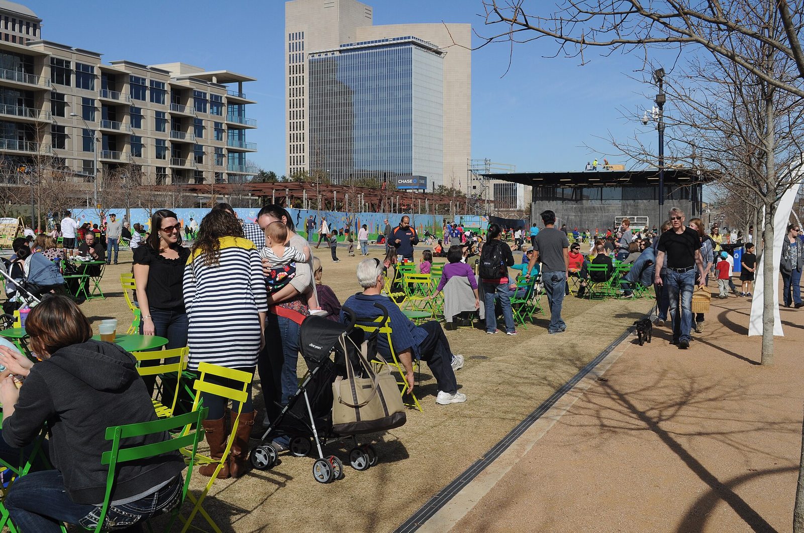 People sitting at green tables and chairs in Klyde Warren Park in Dallas