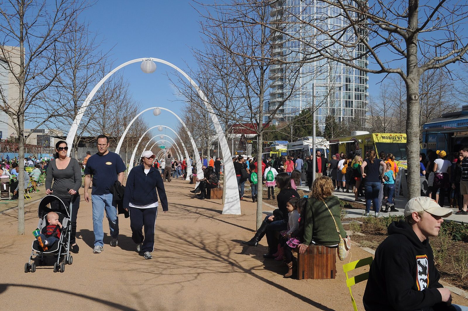 People walking among food trucks and crowds on a busy day at Klyde Warren Park in Dallas