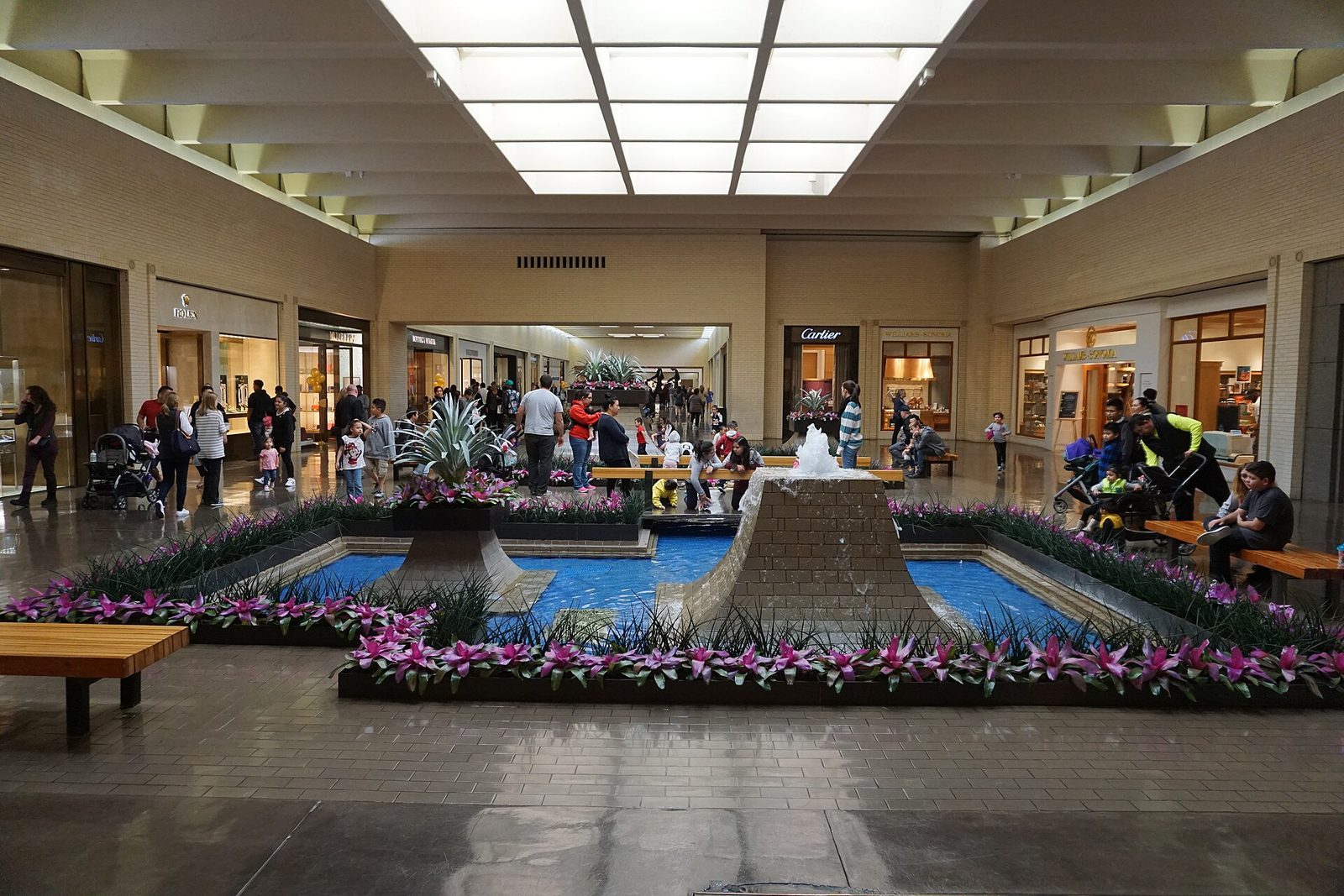 The interior of NorthPark Center in Dallas with a fountain, planting and shoppers