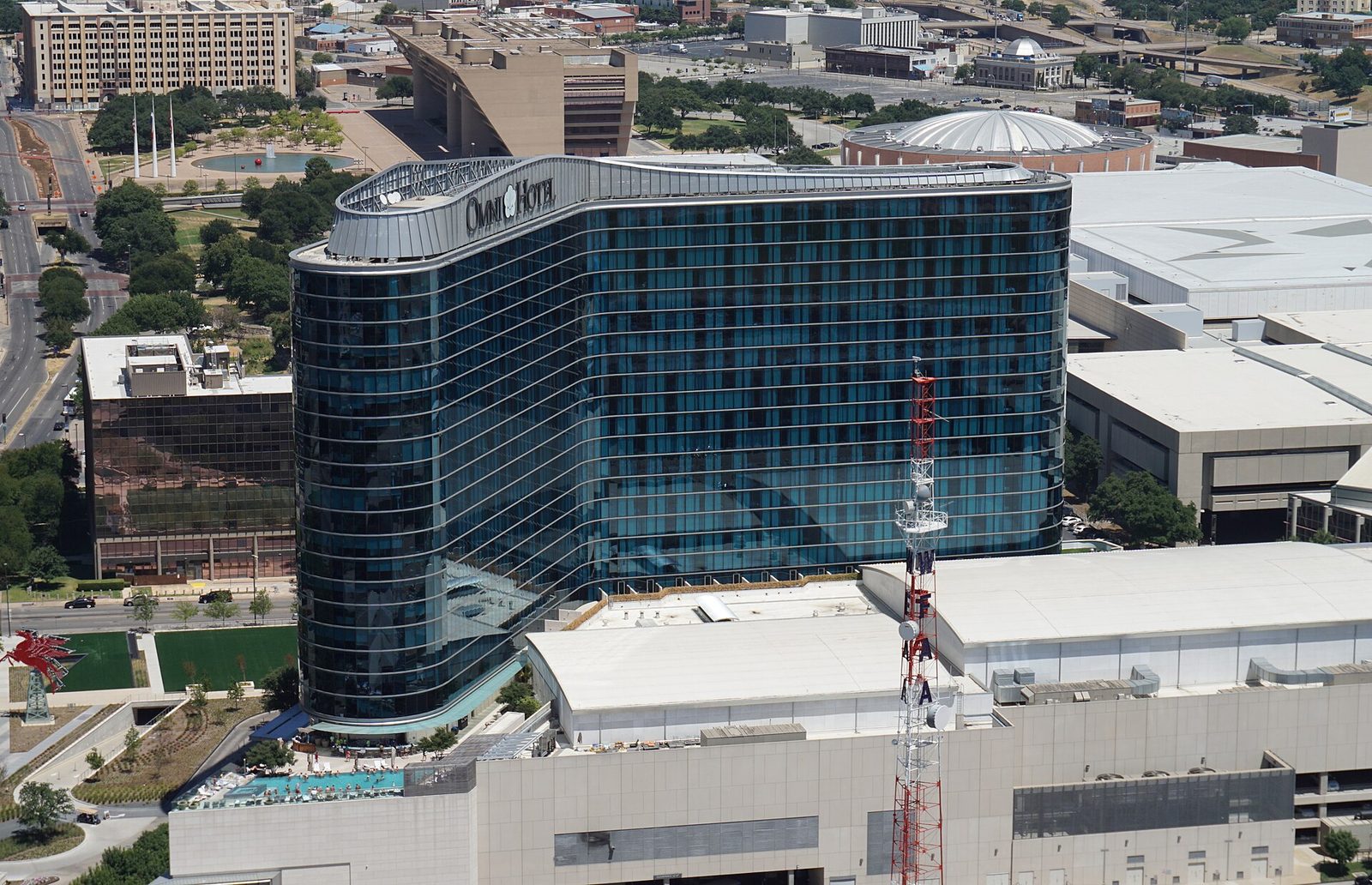A large glass hotel tower beside the convention center in downtown Dallas seen from above