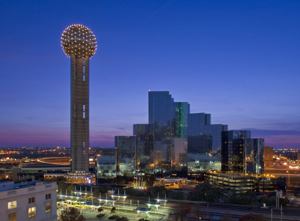 Reunion Tower and the downtown Dallas skyline lit at dusk under a purple sky