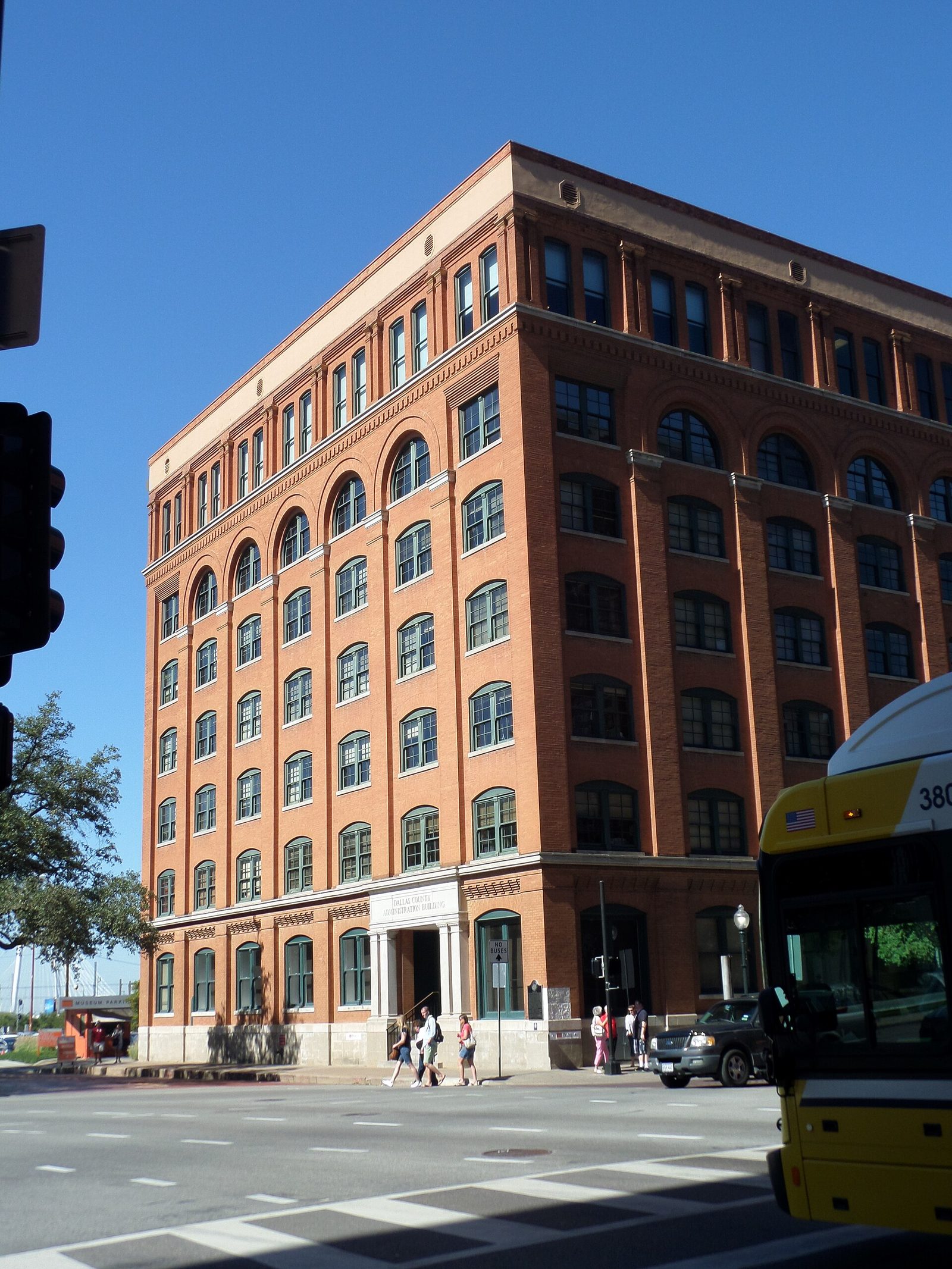 The red brick former Texas School Book Depository building housing the Sixth Floor Museum, with a DART bus passing