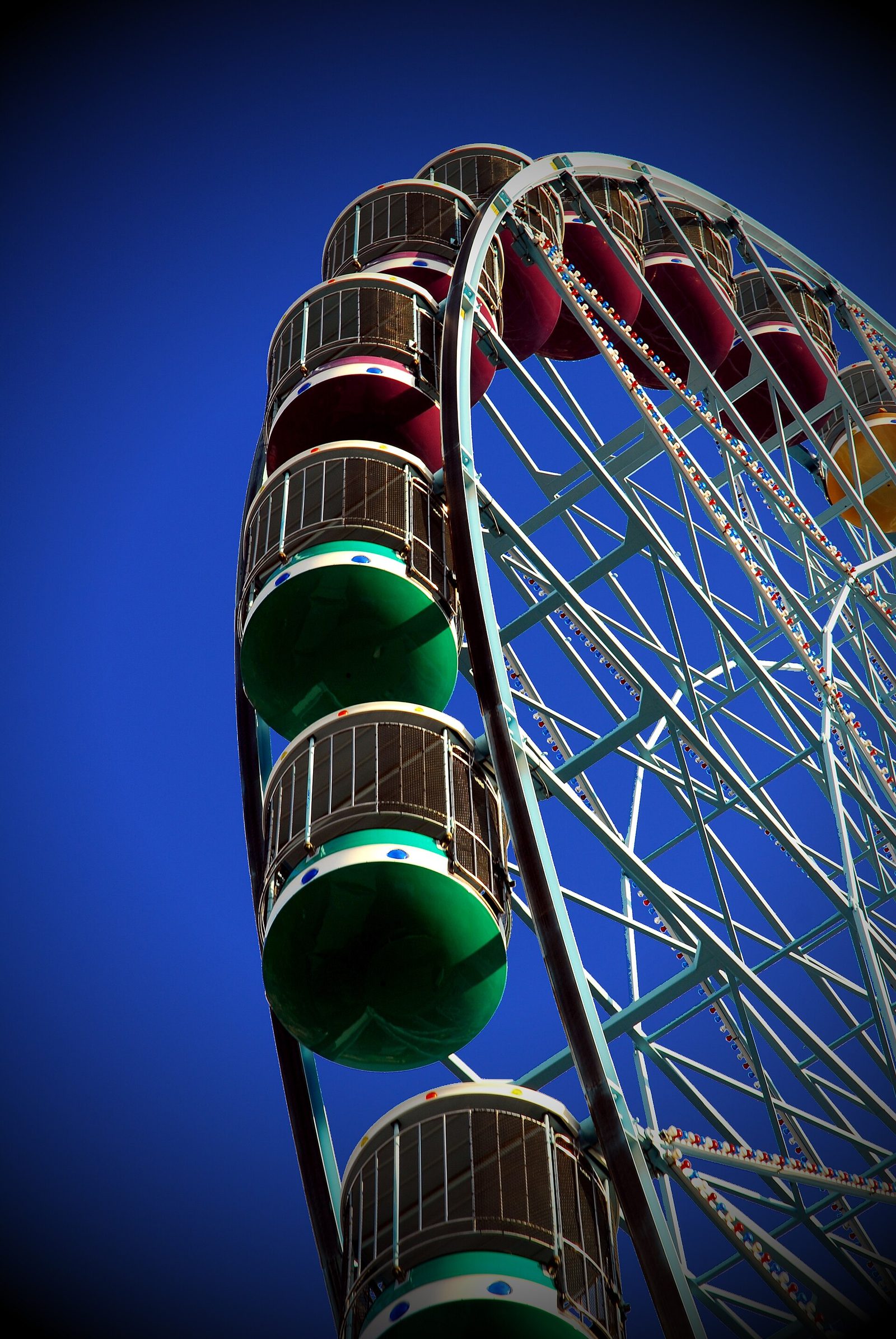 Gondolas of a fairground ferris wheel against a deep blue sky
