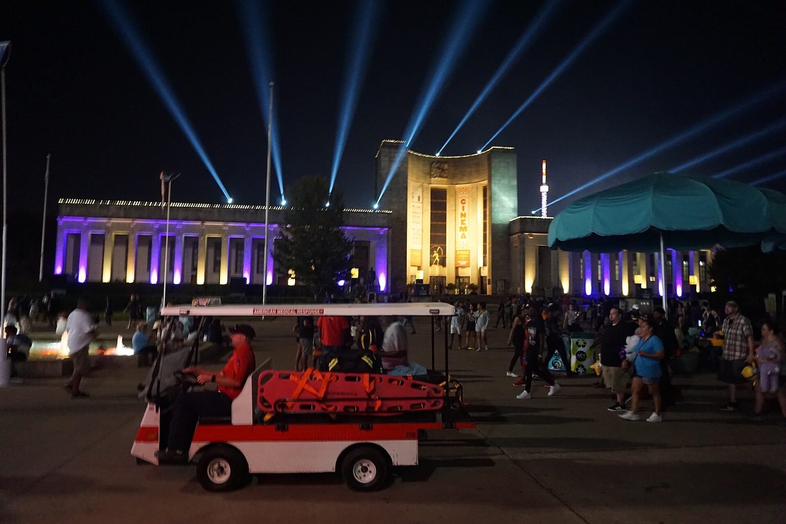 Crowds and a shuttle cart on the Esplanade at Fair Park during the State Fair of Texas at dusk