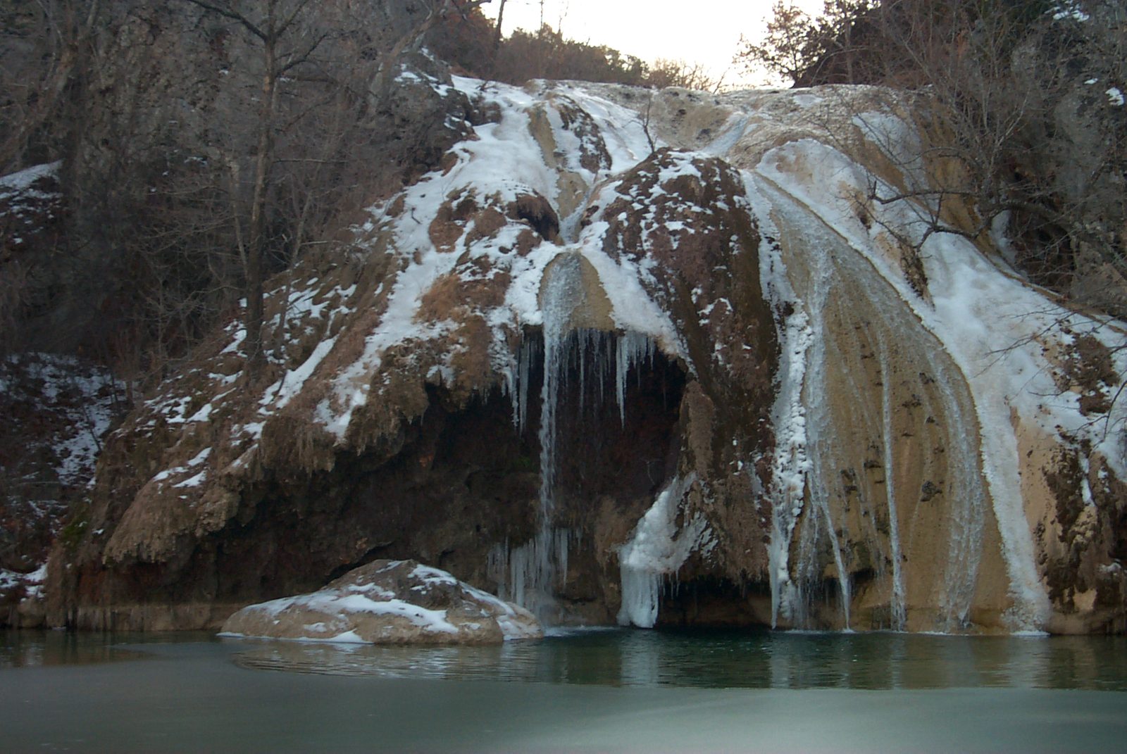 Turner Falls in Oklahoma frozen with ice in winter, the cheapest season for a Turner Falls day trip from Dallas