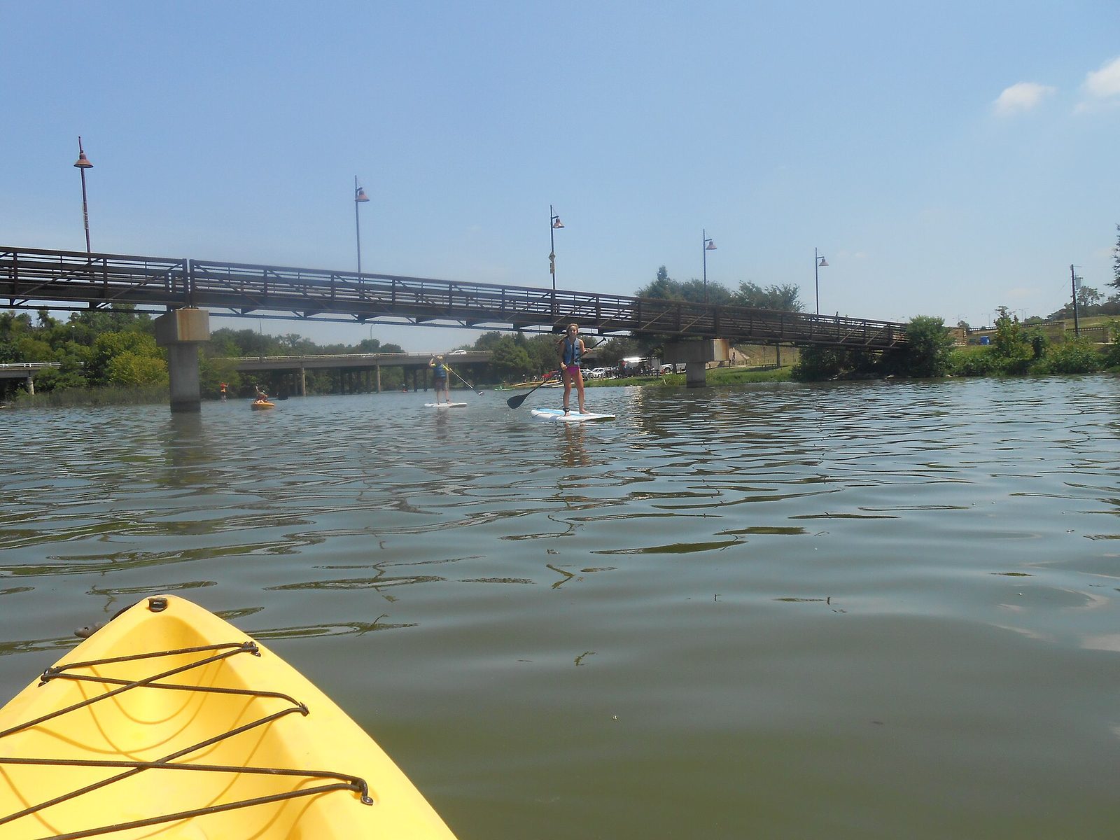 Paddler on the open water at White Rock Lake in Dallas seen from a kayak, with a bridge beyond